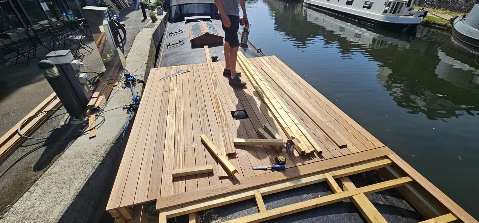 The first hardwood boards laid across the sub-frame, working in from the towpath side