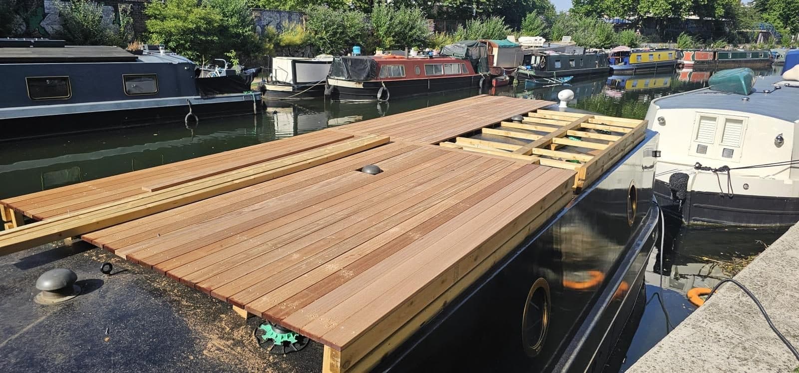 The deck nearly complete, hardwood fascia cladding wrapping the sides of the frame so it reads built-in rather than sat on top