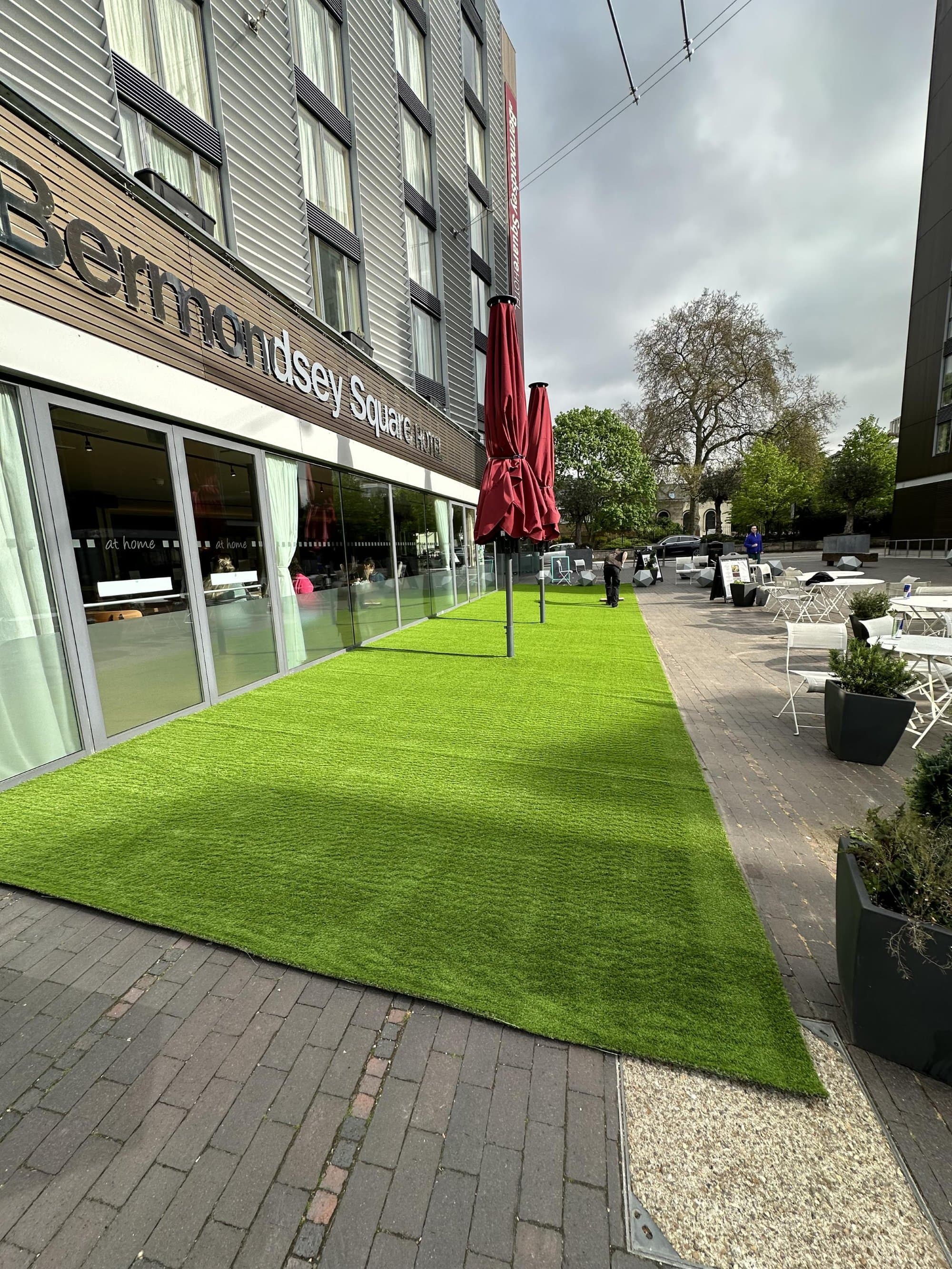 Close view of the bright new artificial lawn where it meets the paving and hotel window