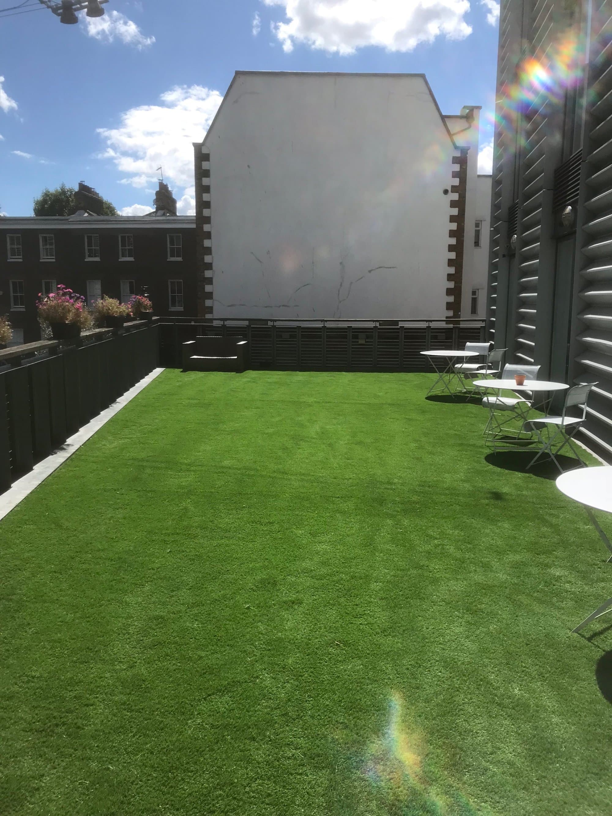 Bright afternoon view of the first-floor terrace with clear blue sky and the fresh lawn running the length of the space