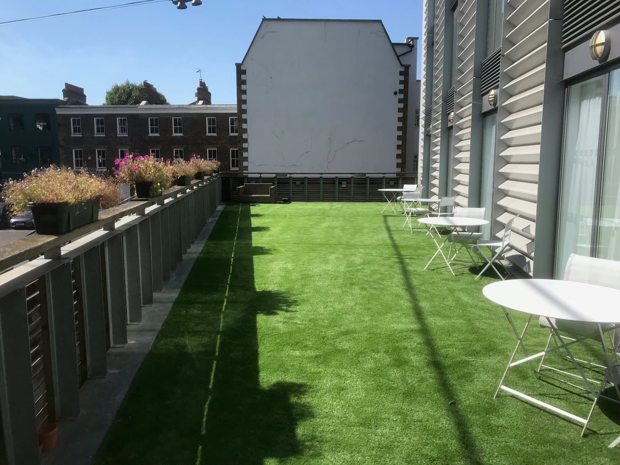 Late afternoon shadows across the finished first-floor terrace, with planters lining the balcony edge
