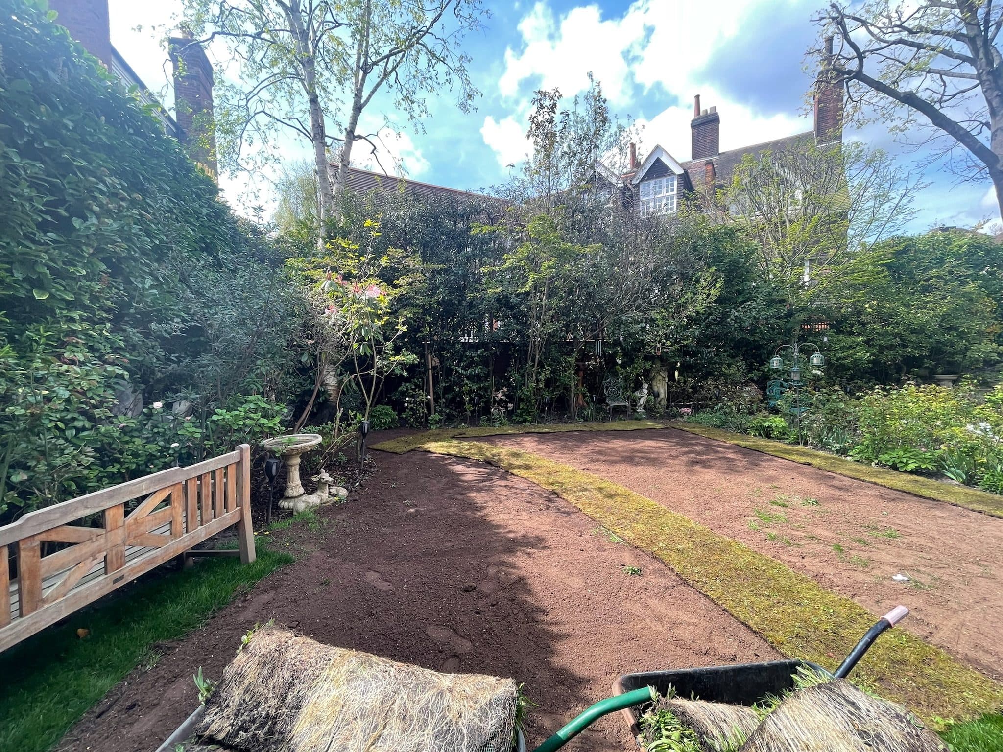 Rolls of meadow turf being laid across the prepared ground