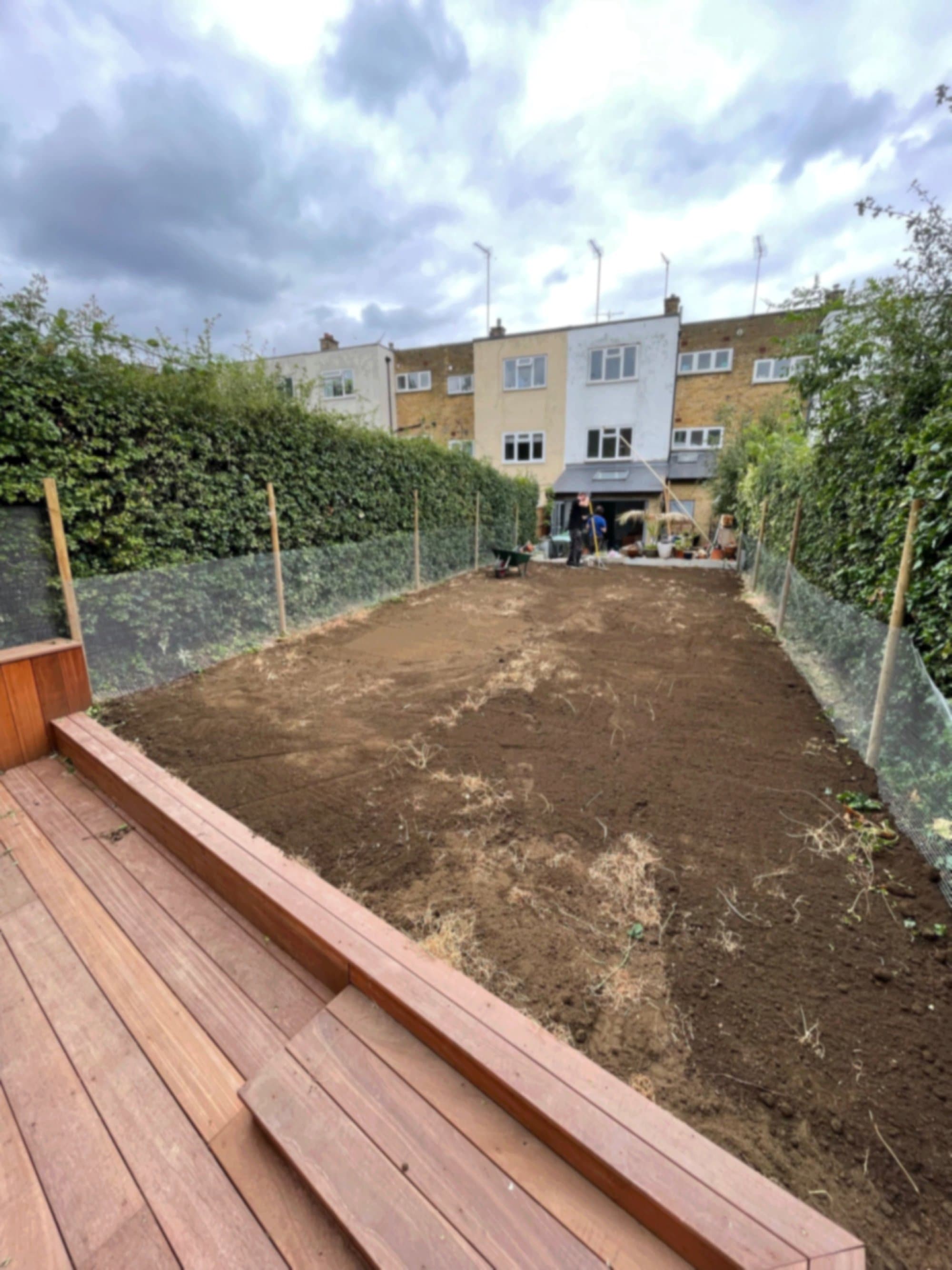 Prepared soil bed ready for the new turf, framed by chainlink fencing