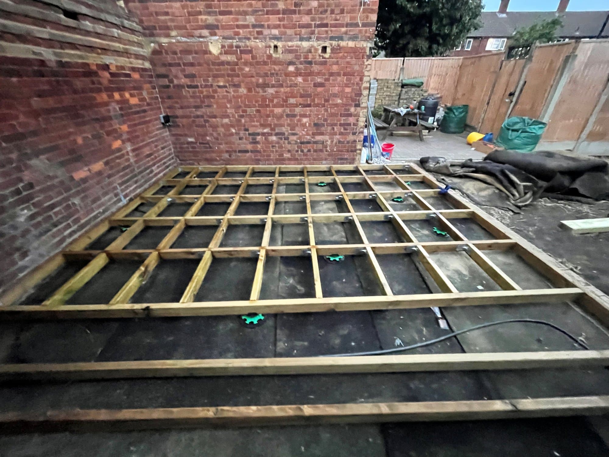 The full deck substructure: joists on adjustable feet over a black weed membrane, ready for boarding