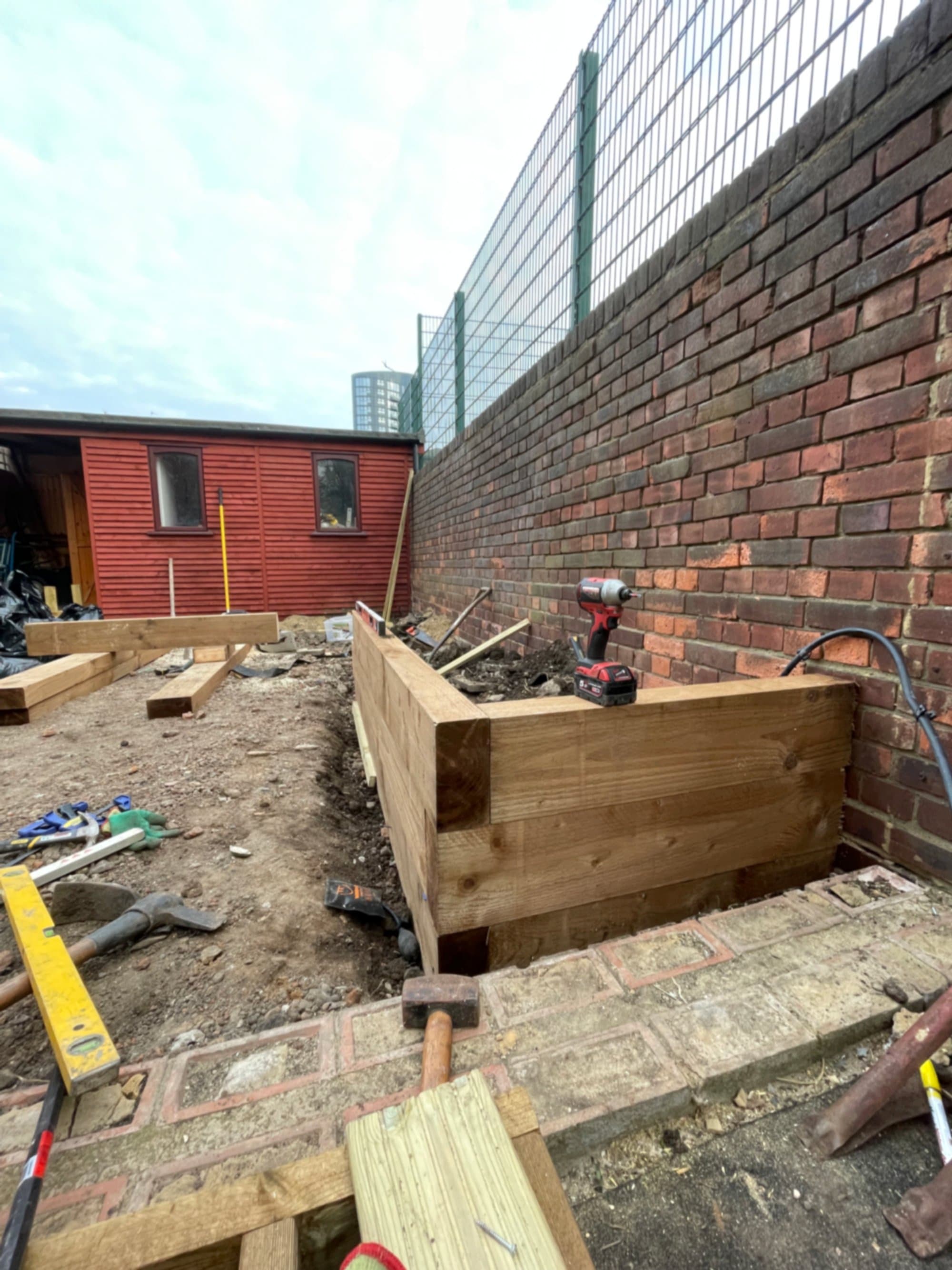 A timber retaining wall and planter being built against the back wall during the build