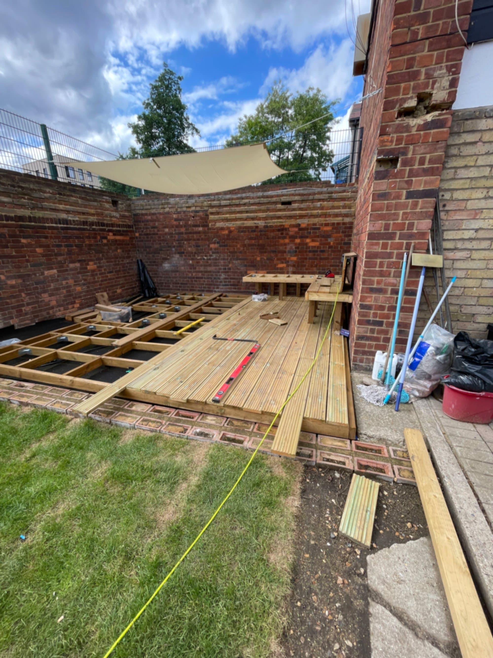 Hardwood decking boards being laid over the joist substructure, with unfinished sections visible on one side